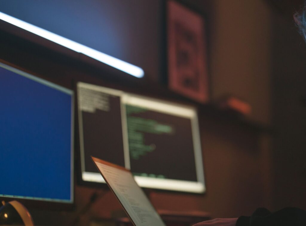 Woman working on cybersecurity programming with laptops and multiple screens